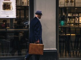 man in black suit jacket and blue hat standing in front of store